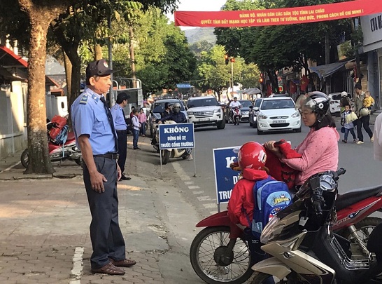 Cán bộ bảo vệ Trường Tiểu học số 2 hướng dẫn phụ huynh đưa đón con dừng, đỗ xe đúng quy định.
